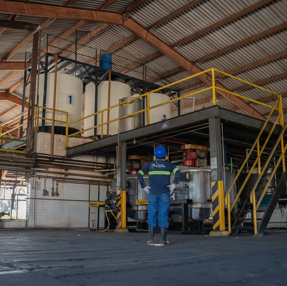 Operario de CTL frente a tanques de formulación en la planta industrial